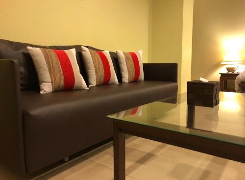a black couch with red and white pillows and a glass table at Hua Hin White Sand in Hua Hin