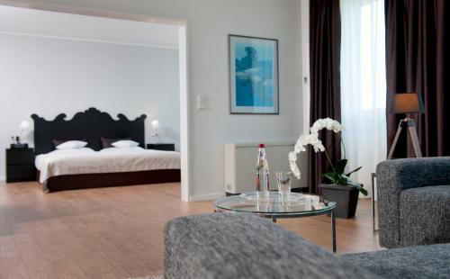 a living room with a bed and a glass table at Wyndham Hannover Atrium in Hannover