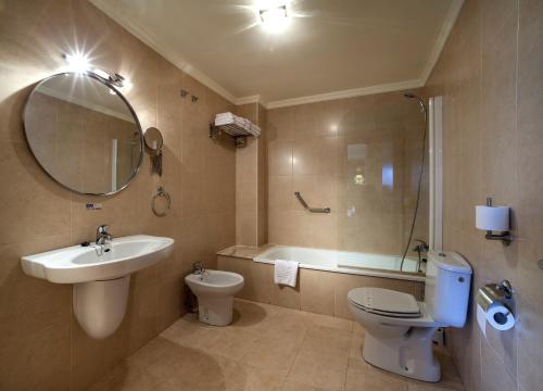 a bathroom with a sink and a toilet and a mirror at Hotel La Polar in Gijón