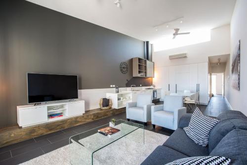 a living room with a couch and a tv at Magnificent Apartment + FREE car park near CBD in Adelaide