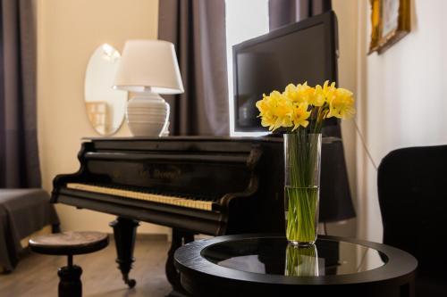 un jarrón de flores amarillas en una mesa junto a un piano en Ozone Private Rooms, en Budapest