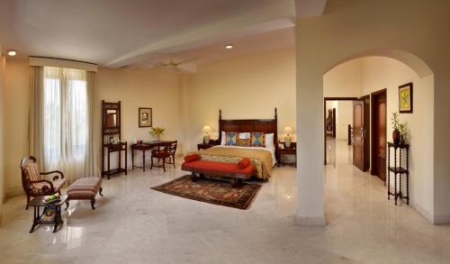 a bedroom with a bed and a table and chairs at The LaLiT Golf & Spa Resort Goa in Canacona