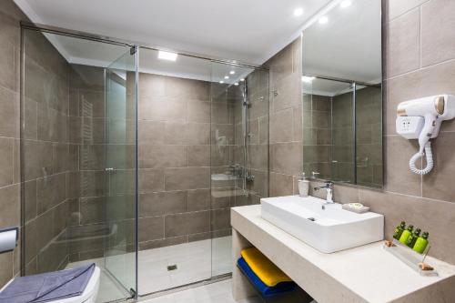 a bathroom with a sink and a shower at Sun and Sea Plus Resort in Plaka