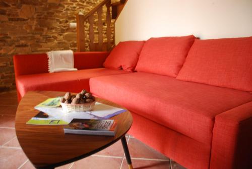 a living room with a red couch and a table at Isabel Artemis ES in San Tirso de Abres