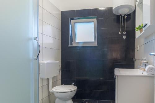 a small bathroom with a toilet and a window at Apartman Berto in Vrsi