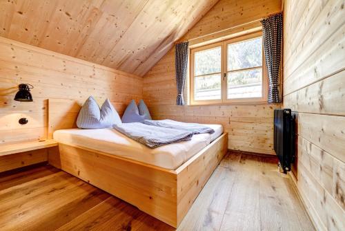 een slaapkamer met een bed in een houten hut bij CASALPIN Chalets in Brand