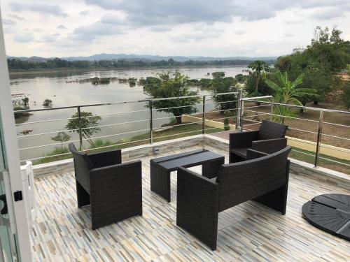a balcony with chairs and a table and a view of a river at Chiang Khan Riverside Pool Villa in Chiang Khan