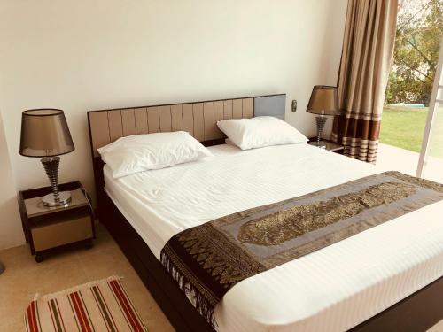a bedroom with a bed with two lamps and a window at Chiang Khan Riverside Pool Villa in Chiang Khan