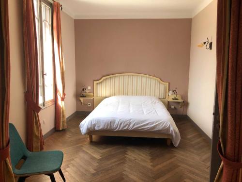 a bedroom with a bed and a chair and a window at Auberge des Lices in Carcassonne