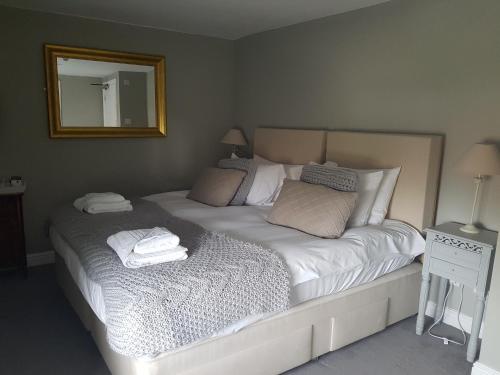 a bedroom with a large white bed with a mirror at The Angel Inn in Warminster