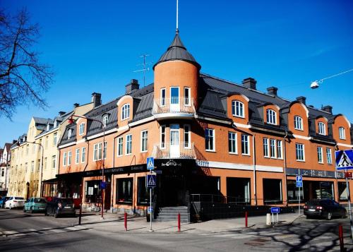 un grand bâtiment en briques rouges avec un toit noir dans l'établissement Huskvarna Stadshotell, à Huskvarna