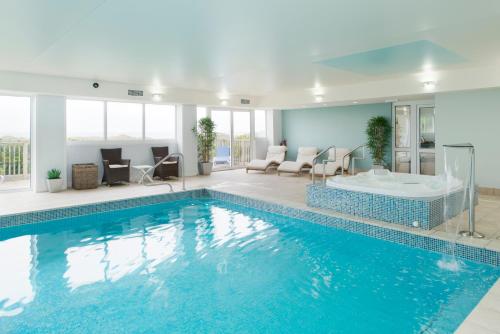 a large swimming pool with a tub in a room at Trefeddian Hotel in Aberdyfi