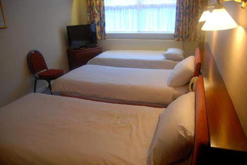 a hotel room with three beds and a television at Brecon Hotel Sheffield Rotherham in Rotherham