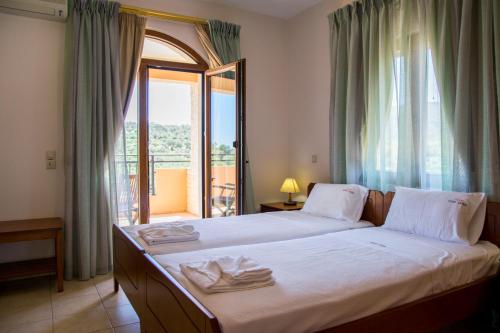 Agia TriadaにあるVilla Tinadoraのベッドルーム1室(ベッド1台付)、窓、バルコニーが備わります。