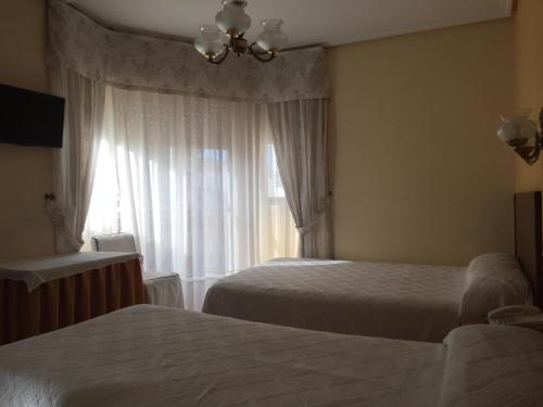 a hotel room with two beds and a window at Hotel Derby in Carballino