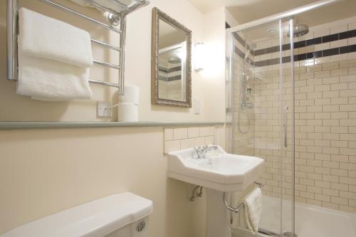 a white bathroom with a sink and a shower at The Duchess of Cornwall in Dorchester