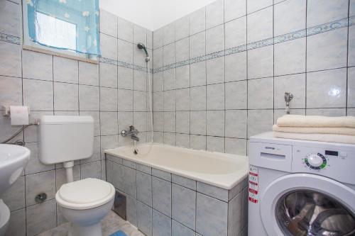 a bathroom with a toilet sink and a washing machine at Apartman Višić 1692 in Kaštela