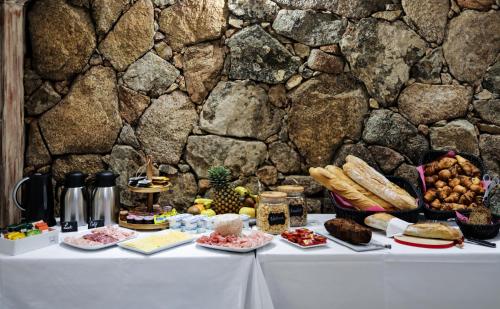 uma mesa com comida ao lado de uma parede de pedra em Macchie e Fiori em Pianottoli-Caldarello