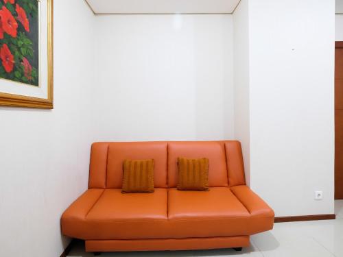 an orange couch with two pillows in a room at Homey 1 BR Apartment Thamrin Residence By Travelio in Jakarta