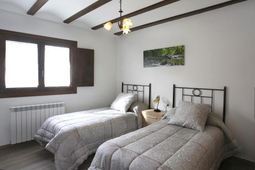 a bedroom with two beds and two windows at Casa Sierra de Guara in Adahuesca
