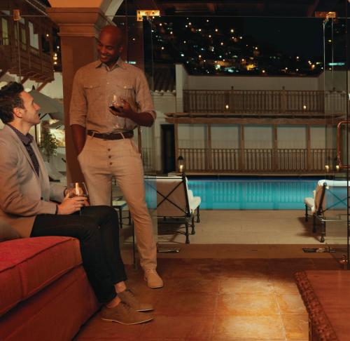 a man standing next to a man sitting on a couch at Palacio Nazarenas, A Belmond Hotel, Cusco in Cusco