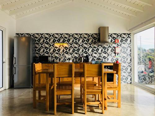 eine Küche mit einem Tisch und Stühlen sowie einem Kühlschrank in der Unterkunft Casa da Rocha in Terra do Pão