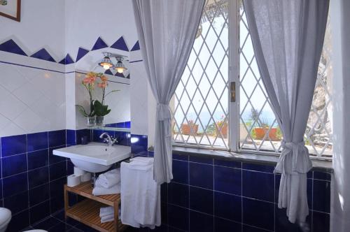 een blauwe en witte badkamer met een wastafel en een raam bij Star Fish House in Amalfi