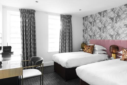 a hotel room with two beds and a desk at The Lodge Hotel - Putney in London