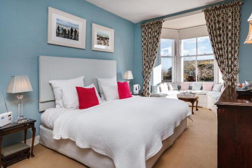 um quarto com uma grande cama branca com almofadas vermelhas em Newton Cottage em Porthcawl