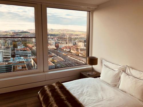 a bedroom with a view of a city from a window at Park Tower City View Apartments in Zug