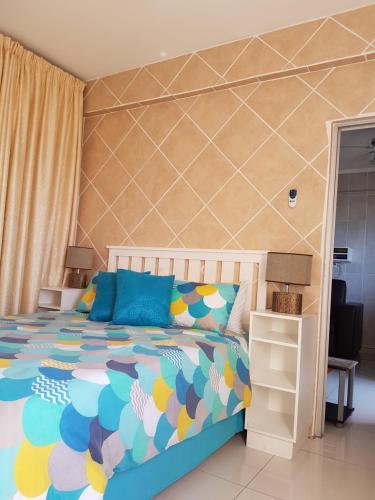 a bedroom with a bed with a colorful bedspread at Beach frond apartment in Amanzimtoti