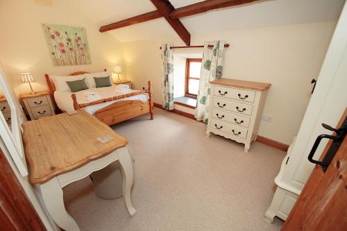 a bedroom with a bed and a table in it at Cilhendre Holiday Cottages - The Dairy in Swansea