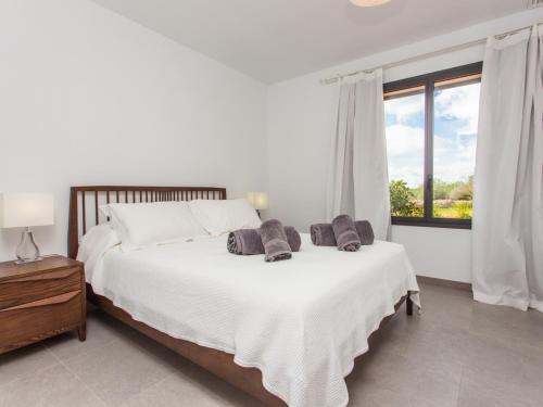 ein weißes Schlafzimmer mit einem großen Bett und einem Fenster in der Unterkunft Villa Can Paulo in Santanyi