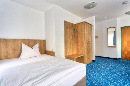 a bedroom with a white bed and a wooden cabinet at Appartis - Hotel am Stadtpark in Sindelfingen