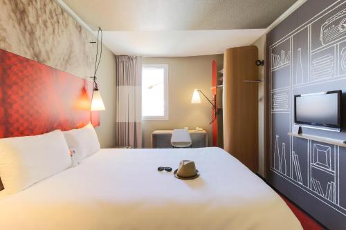 a hotel room with a bed with a hat on it at ibis Carcassonne Est la Cité in Carcassonne