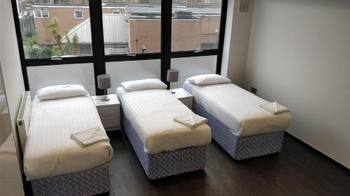 twee bedden in een kamer met een raam bij Access Tower Hill in Londen
