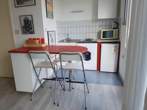 a kitchen with a red counter and three stools at Bordeaux Red and Rouge in Bordeaux