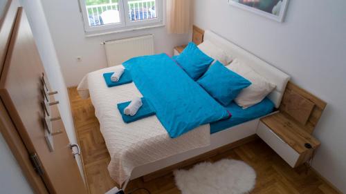 uma pequena cama num pequeno quarto com almofadas azuis em Zen Voyage em Zagreb