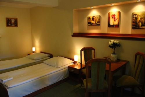 a hotel room with two beds and a table with candles at Karczma Rycerska Lebork in Lębork