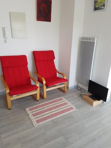 two red chairs and a television in a room at Bordeaux Red and Rouge in Bordeaux