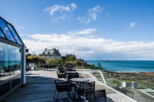 a balcony with tables and chairs and a view of the ocean at Emeria Dinard Thalasso Spa in Dinard