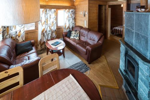 a living room with leather furniture and a fireplace at Tundrea Holiday Resort in Kilpisjärvi