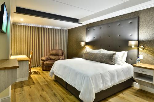 1 dormitorio con 1 cama grande y 1 silla en HERMS Restaurant & Boutique Hotel, en Port Elizabeth