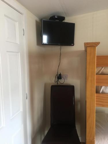 a television on the wall of a room with a chair at 1 Lochness Rooms&Hostel in Drumnadrochit