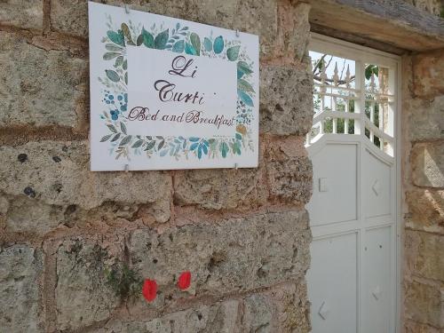 a sign on a brick wall with a white door at LI CURTI B&B in Melissano