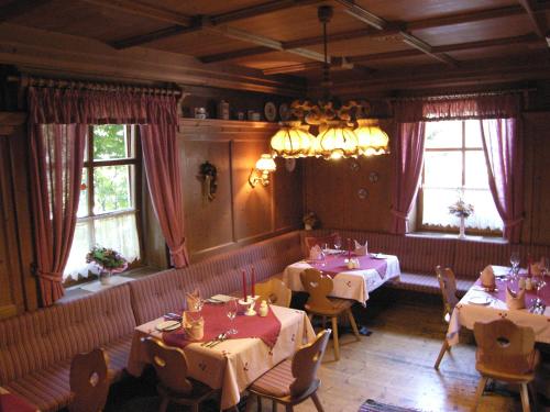 uma sala de jantar com mesas, cadeiras e janelas em Gasthof Safenhof em Bad Waltersdorf