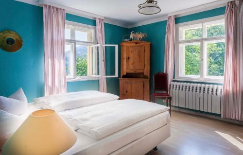 a bedroom with a bed with blue walls and windows at Haus Hohlfeld in Bad Schandau