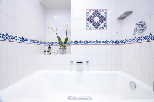 a white bathroom with a sink and blue and white tiles at DieciSedici in Amalfi