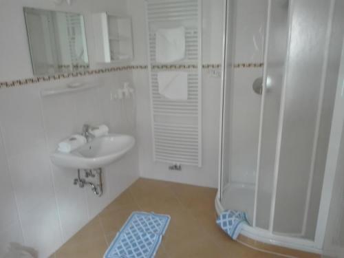 a white bathroom with a sink and a shower at Hotel Haselried in Tirolo