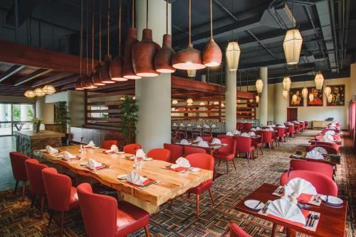 a dining room with a long table and red chairs at Mövenpick Hotel & Residences Nairobi in Nairobi
